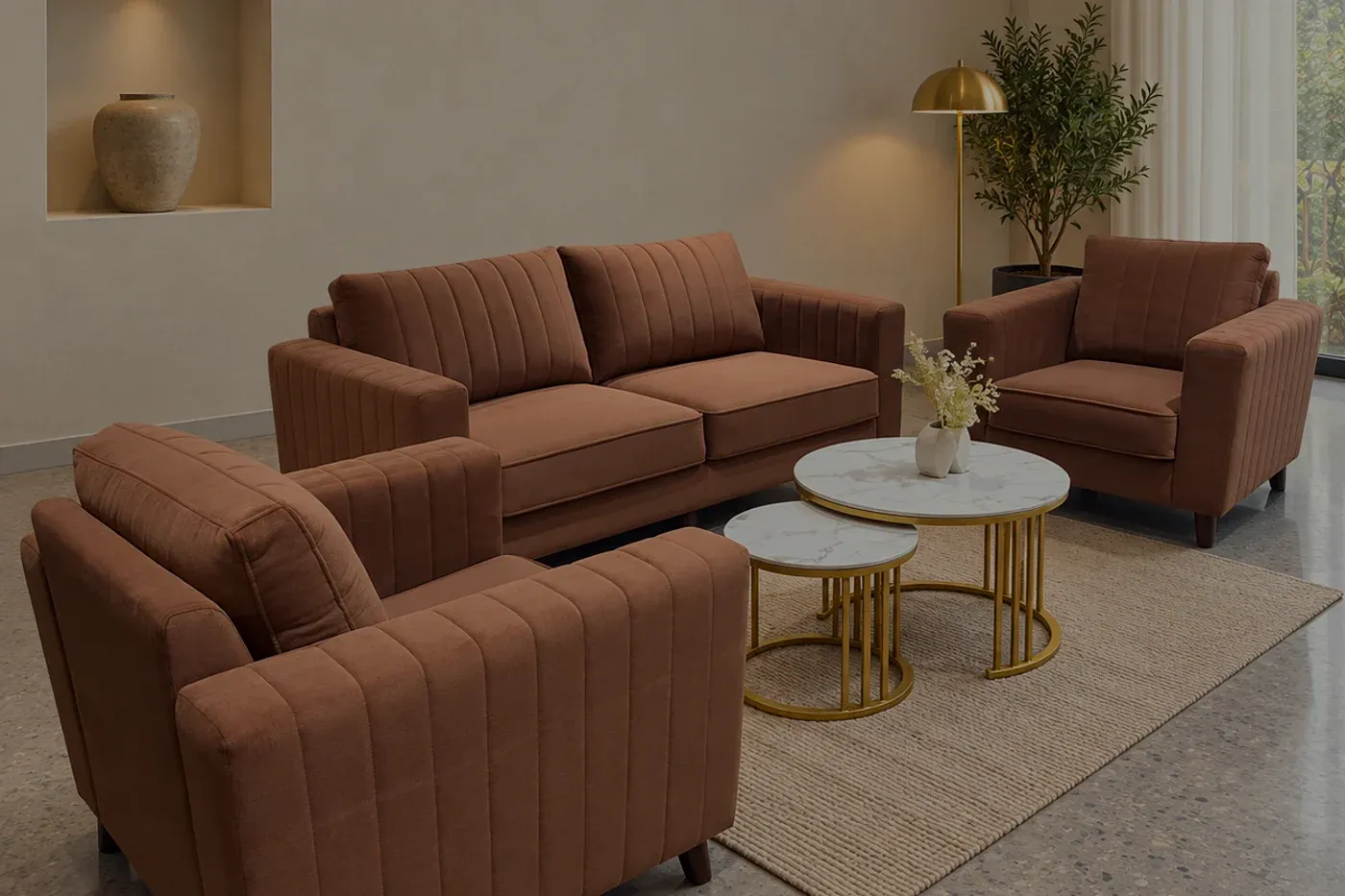 A brown channel-stitched sofa and armchair on a terrazzo floor, a recessed niche holding a single ceramic vessel.