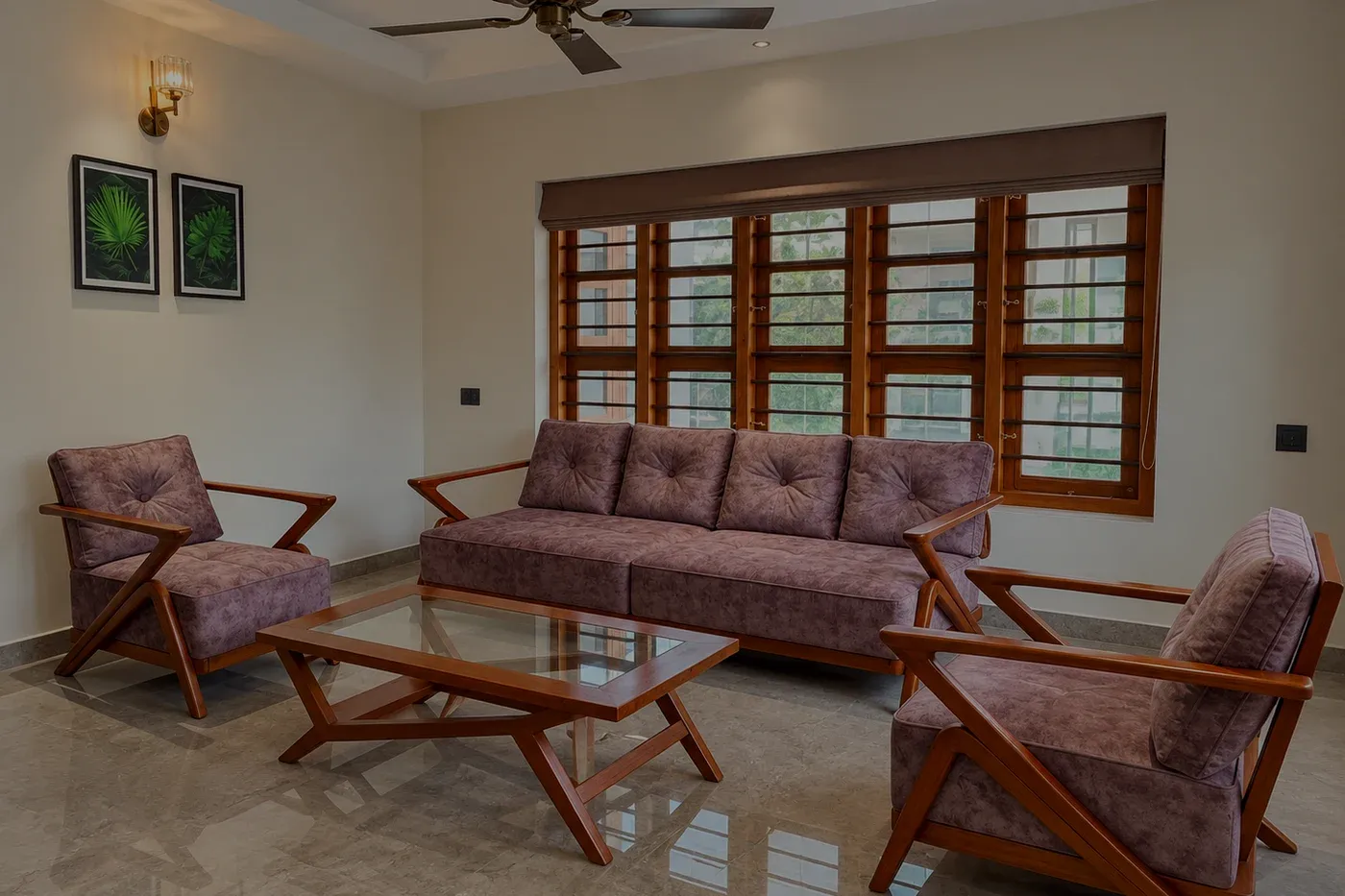 A mauve buttoned sofa under a barred window with two matching armchairs on a polished stone floor.