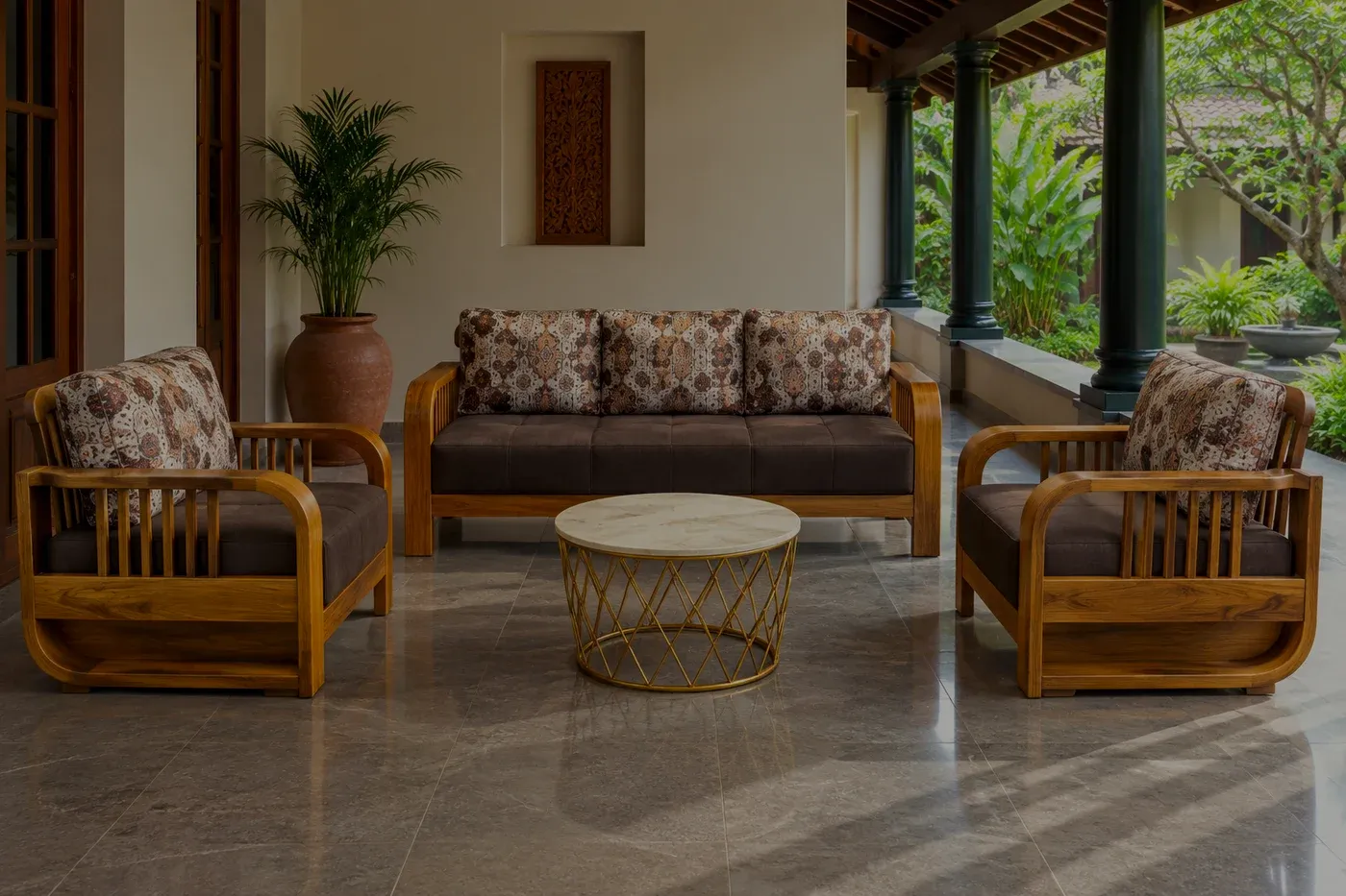 A slatted wooden sofa set with dark cushions on a veranda, a colonnade along one side opening onto a planted courtyard.