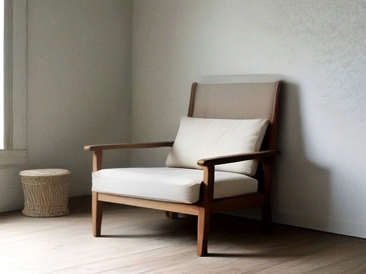 A teak armchair with a low back and worn cane seat, lit from one side.