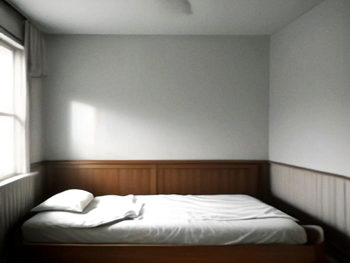 A low teak bed frame with a plain headboard and white bedding, seen from the foot in soft daylight.