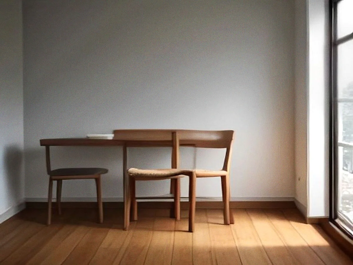 Two teak chairs with caned seats drawn up to a small table, side-lit from a window.