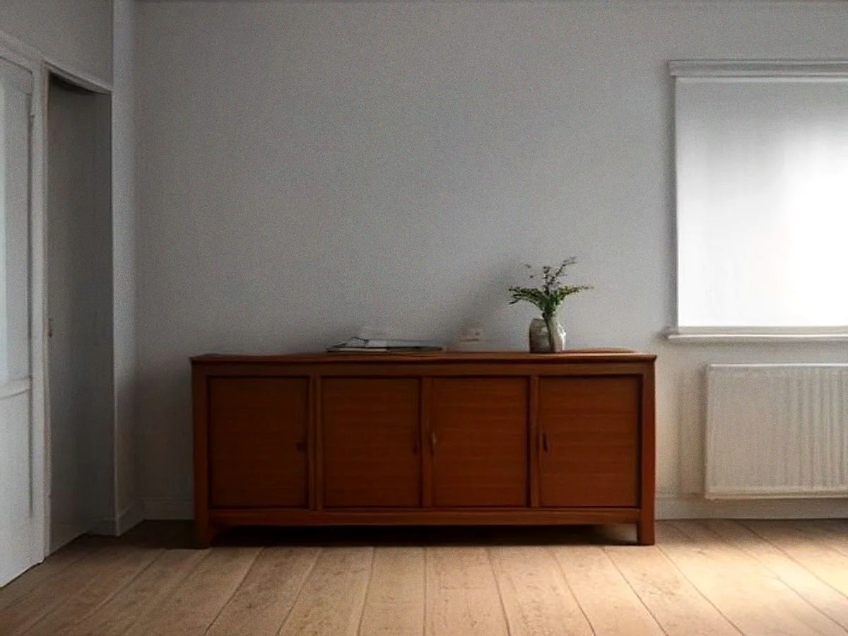 A long teak sideboard photographed straight on against a bare plaster wall.