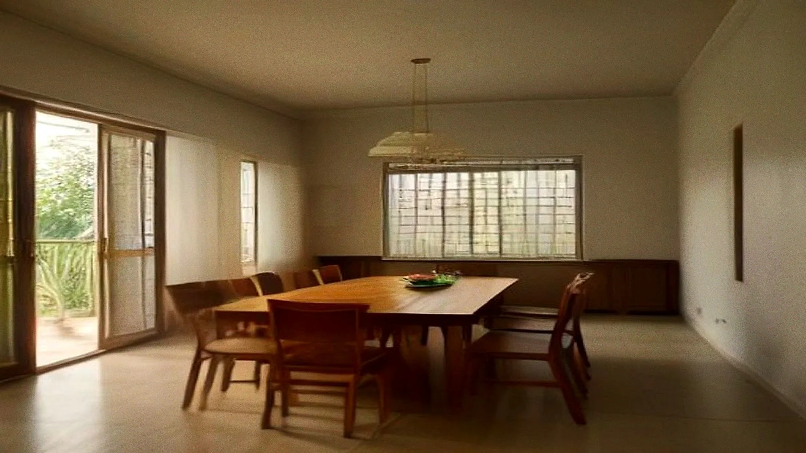A dining table in early morning light with four chairs left pulled out at angles, shutters open onto a garden.